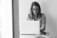 Eine Frau arbeitet Hybrid mit ihrem Laptop an einem Tisch in schwarz-weiß