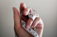 Weißes Maßband ist um eine Hand gewickelt