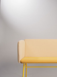 Gelbes Sofa steht vor grauer Wand